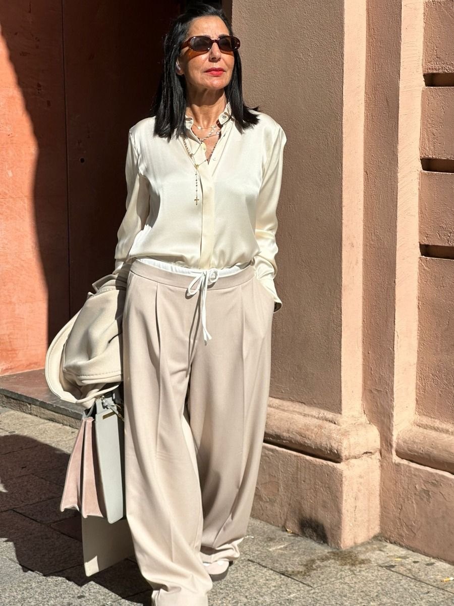 Áo lụa trắng, quần ống rộng be, khoác trench coat (hoặc blazer) layer.